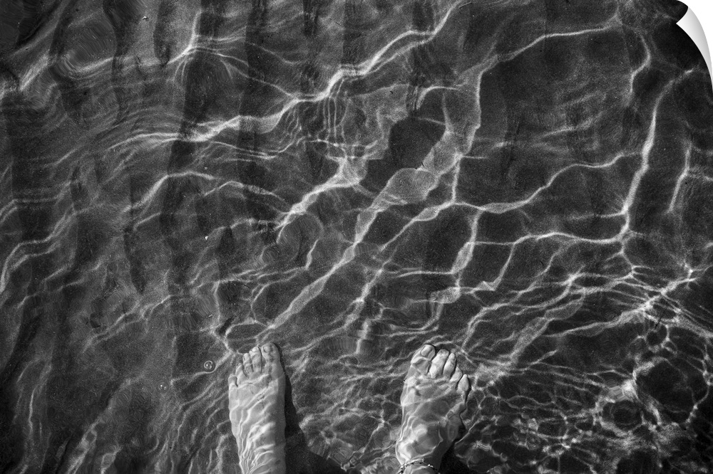 A woman's feet in the sand, through the crystal clear water, in the beach