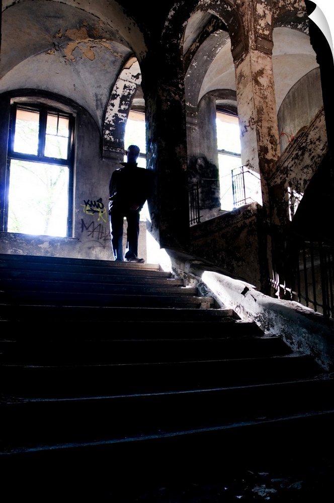 Silhouette of a man standing on some old stairs in a large building