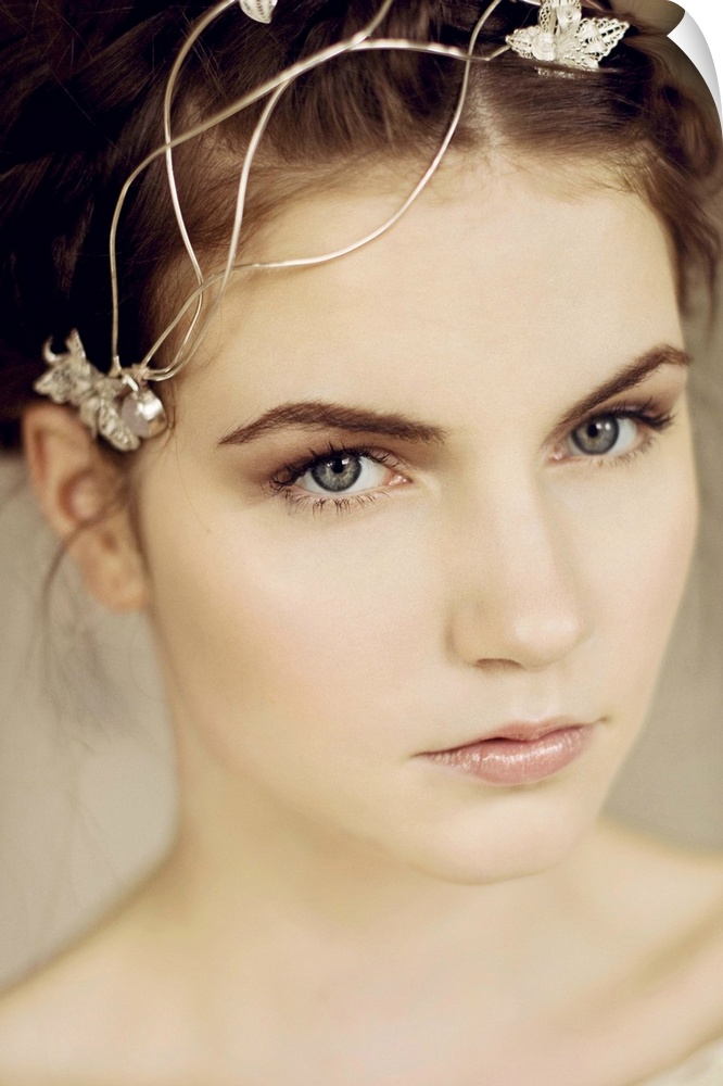 Close portrait of young woman with silver headpiece and braided hair looking into the camera