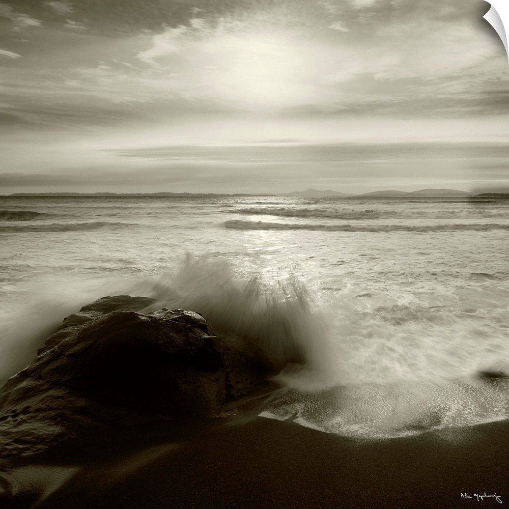 Black and white photograph of a seascape with the ocean waves hitting the rocky shoreline.