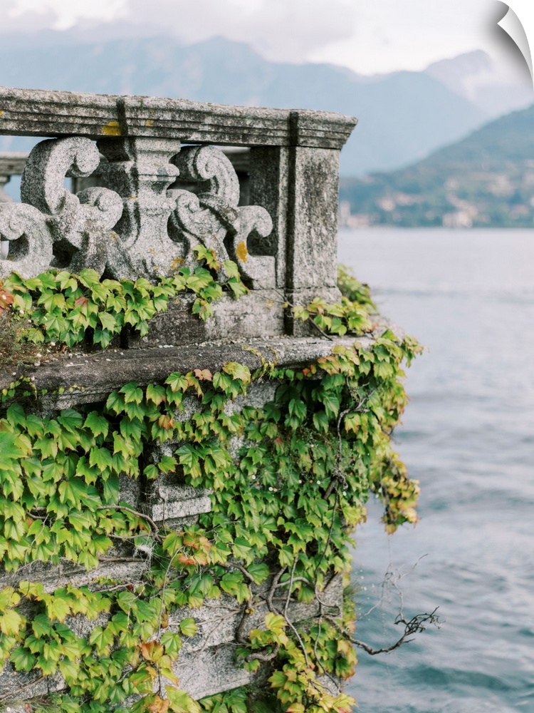 A photograph of an ornate stone balcony covered with ivy on the shore of Lake Como, Italy.