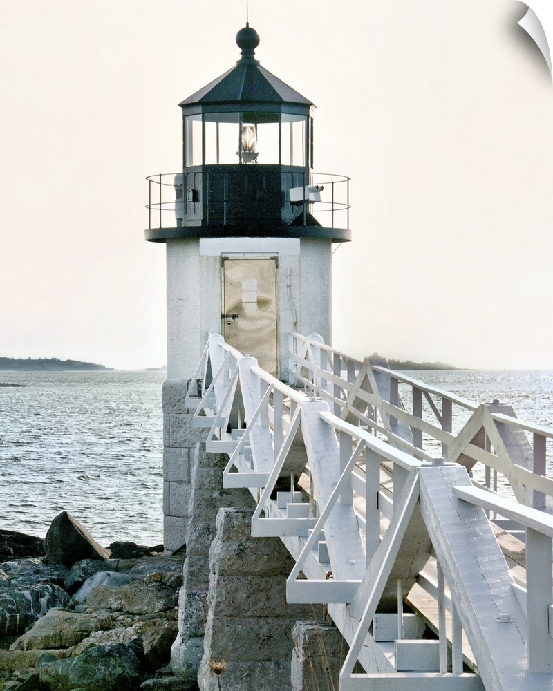 A photograph of a lighthouse at the end of a pier jetting out over the water.