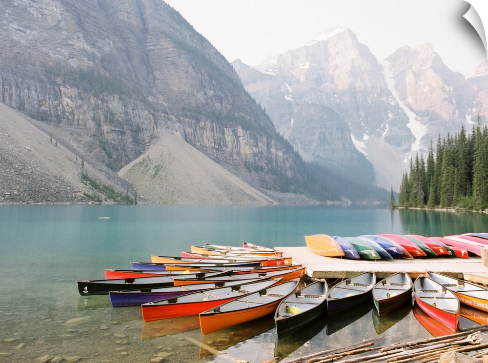 A photograph of colorful canoes on the edge of Moraine Lake, Banff National Park, Alberta, Canada.