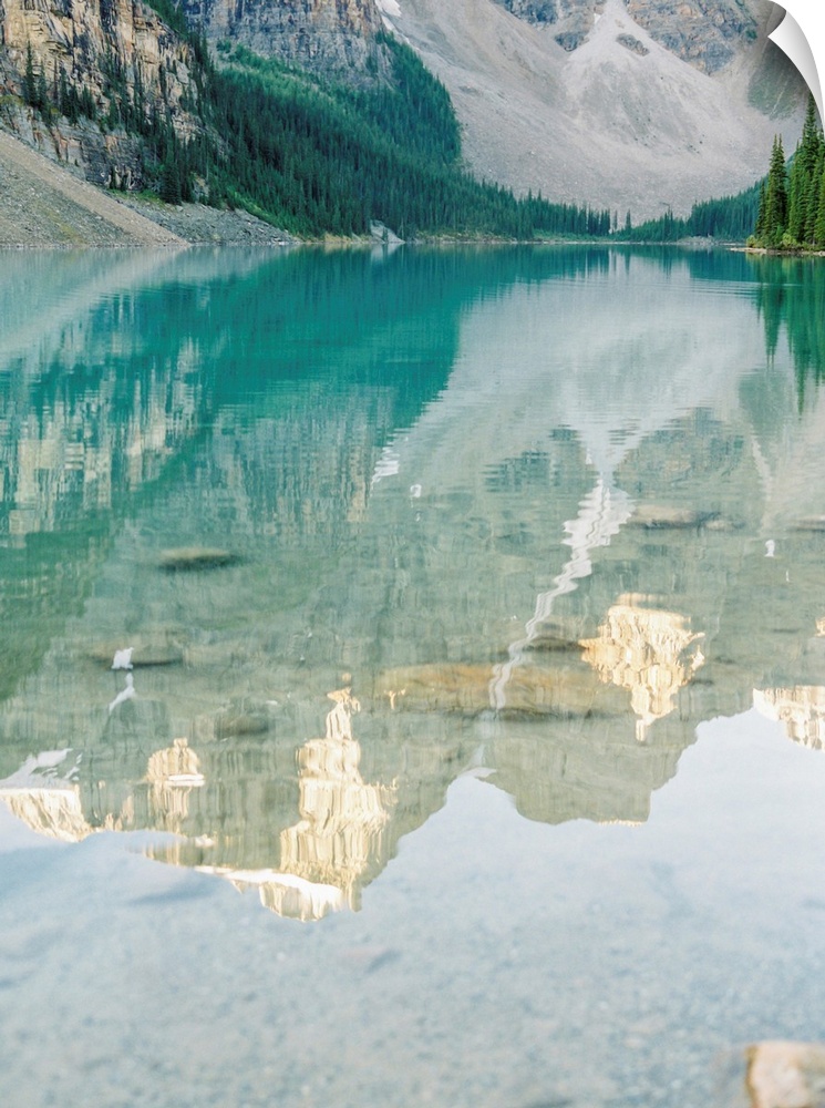 A photograph of mountains reflecting in the clear blue water of Moraine Lake, Banff National Park, Alberta, Canada.