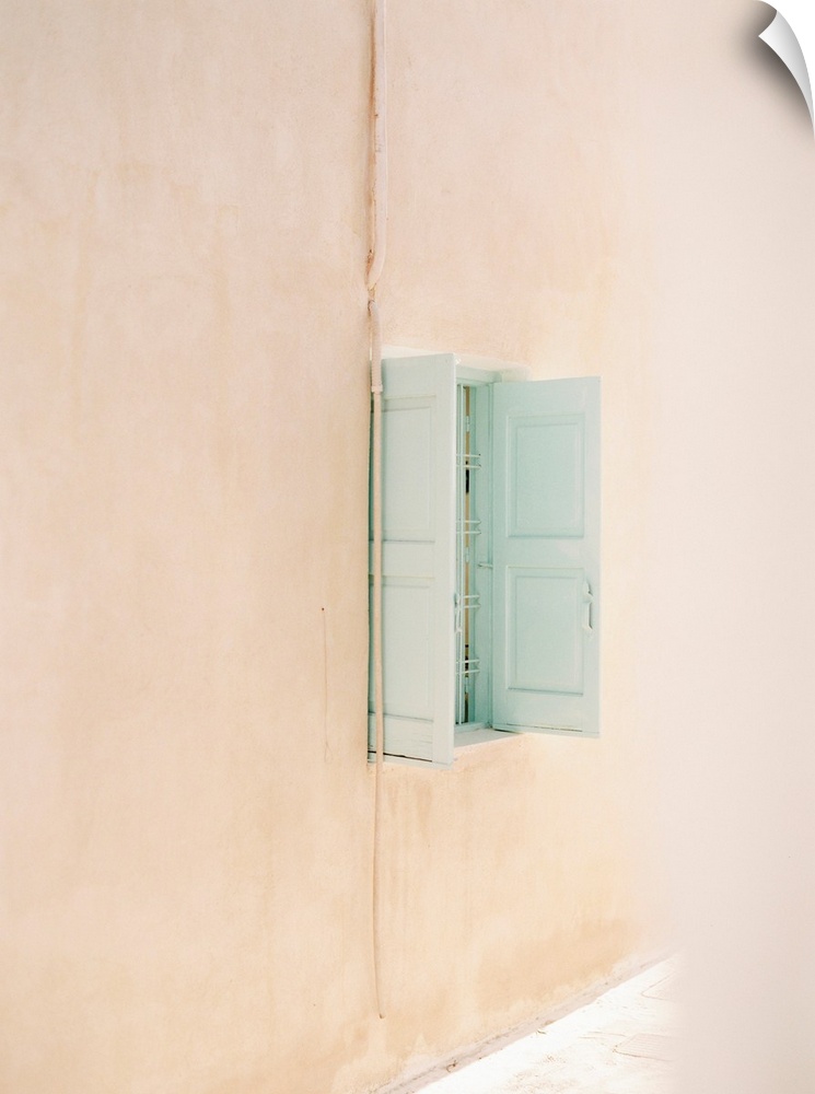 Photograph of a small window with pale blue shutters in a peach colored wall.