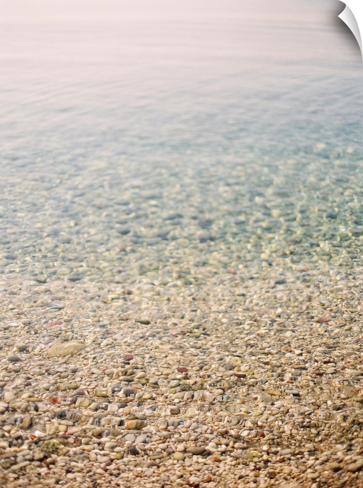 Photograph of shallow ocean water on a pebble beach, Corfu, Greece.