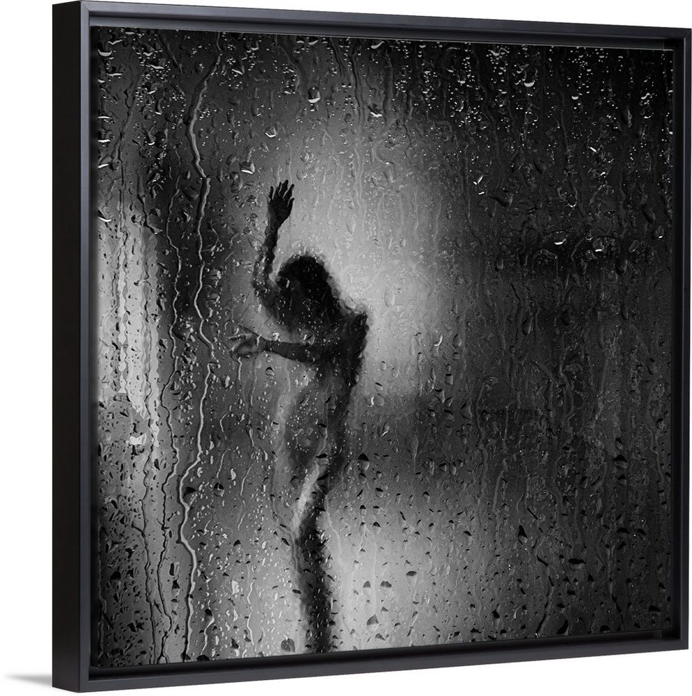 Square black and white fine art photograph of a nude woman through a rainy window glass.