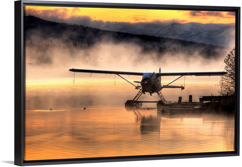 Giant photograph displays a seaplane sitting next to a dock as a soft fog rolls over the water.  In the background, the fa...