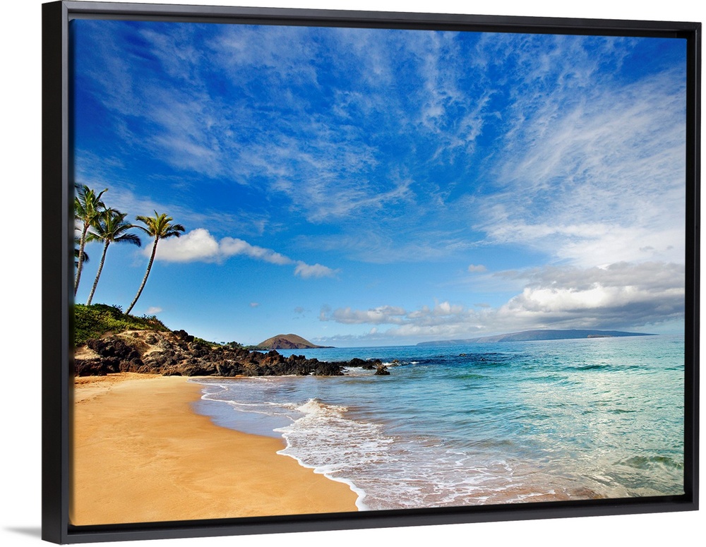 Tropical beach with small, calm waves under a partly cloudy sky, with a few palm trees in the distance.