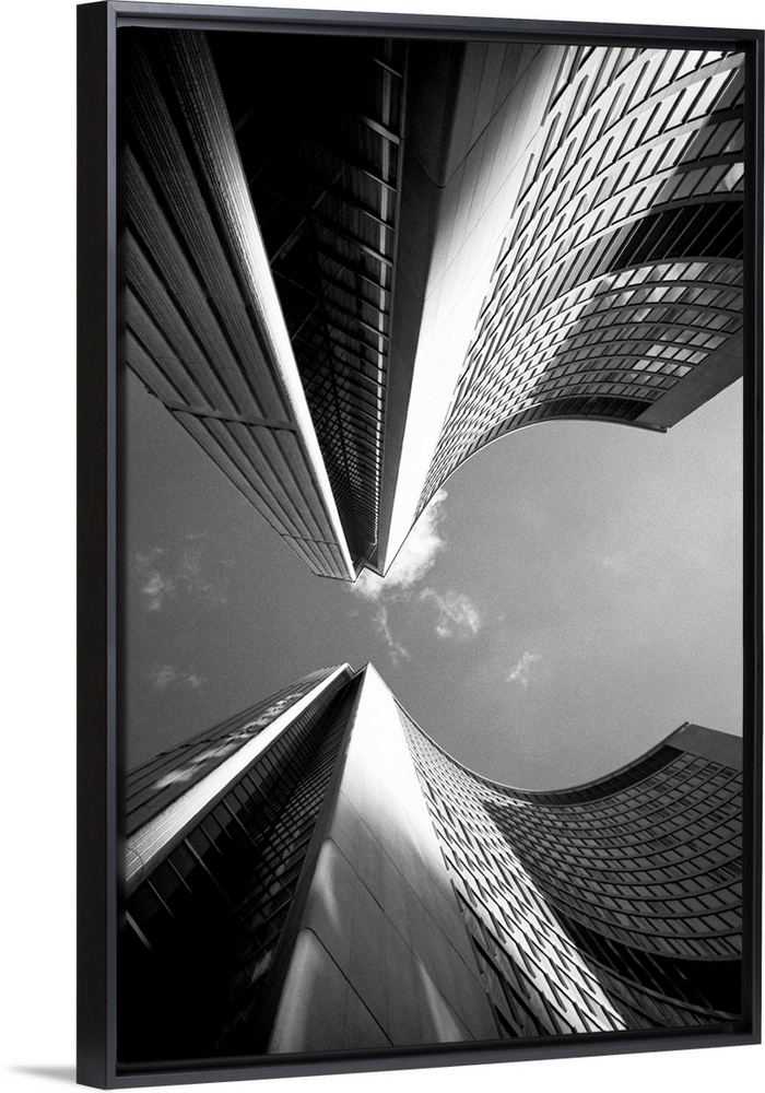 Black and white photograph of a view looking straight up between two skyscrapers in a city.