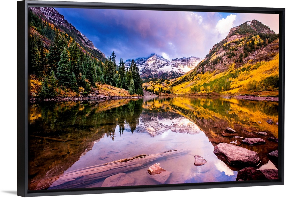 There is a warm hue to this photograph of mountainous terrain and thick foliage that reflect in still water below.