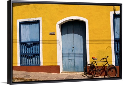 Old yellow building in colonial town of Trinidad Cuba with bike against wall