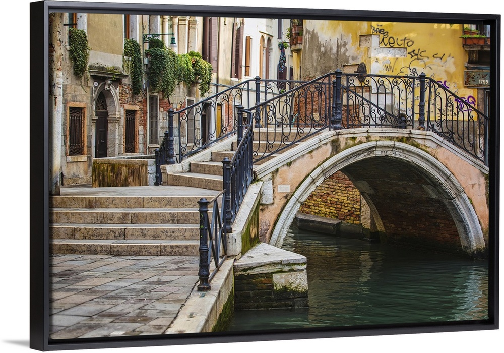 Narrow canal among old colorful brick houses in Venice, Italy.