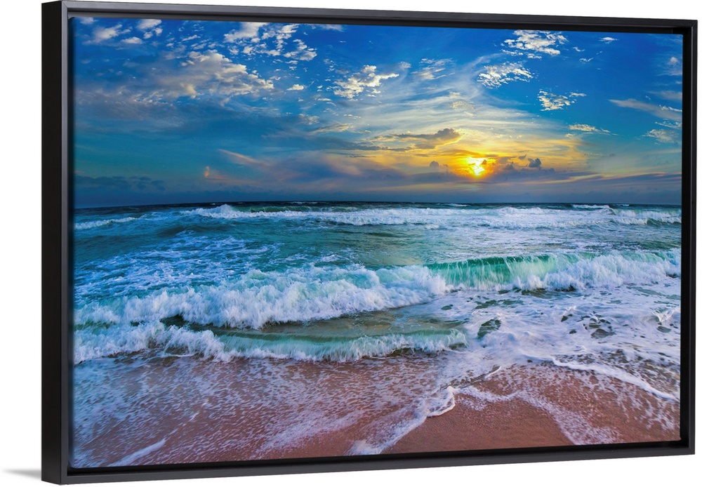 A glimpse of a yellow sunset within a cold blue sunset. Blue waves hit a tropical sea shore.