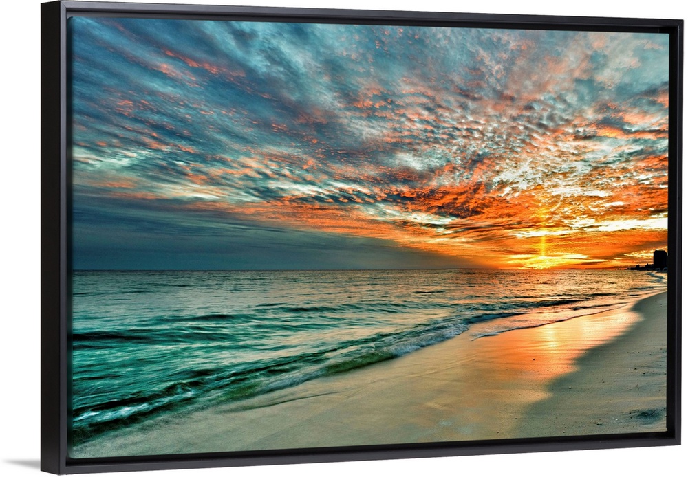 A bright yellow sunray of light shoots up from the sunset into the dark red evening sky. Emerald waves with a red and blue...