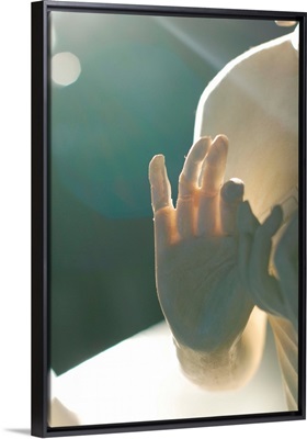 Buddha figure's hand is illuminated from behind.