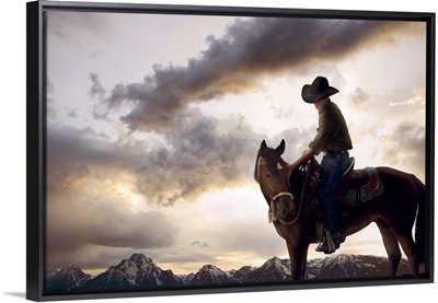 Cowboy on horse looking at mountain range, dusk, low angle view