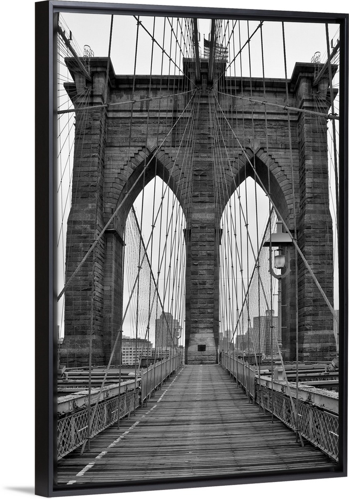 Large, vertical black and white photograph of one of the stone piers surrounded by many cables on the Brooklyn Bridge in N...