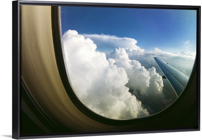 Watching the clouds pass by through a window of an airplane