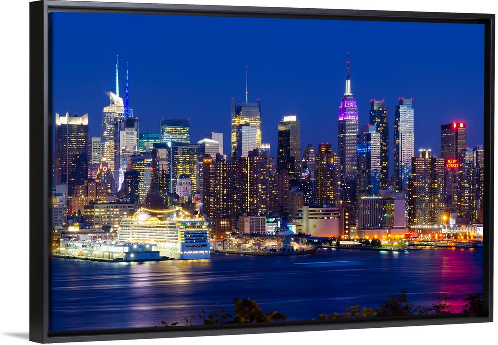 Canvas print of the NYC cityscape lit up in colored lights along a waterfront.