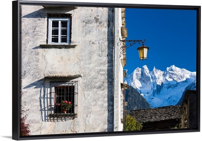 Typical alpine house and street lantern frame the snowy peaks Soglio Bregaglia Valley