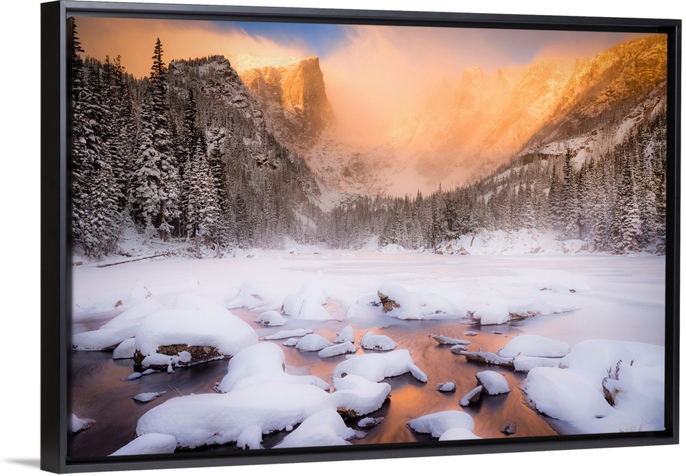 Giant photograph of a snow covered landscape filled with trees surrounding and a frozen river running down the center of t...