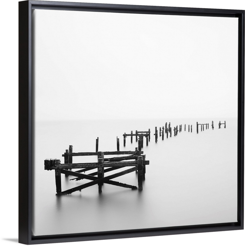 Large photograph focuses on a deteriorating dock sitting alone in a wasteland of fog.