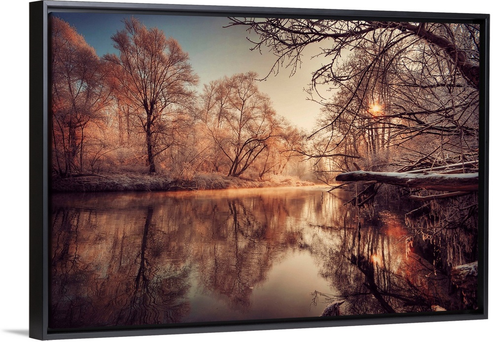 In this landscape photograph morning light reflects off a river in a forest covered with the first frost.