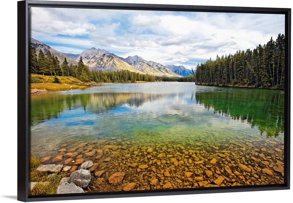 Giant photograph taken from the rocky shores of a lake that is surrounded by dense forests and snow covered mountains in t...