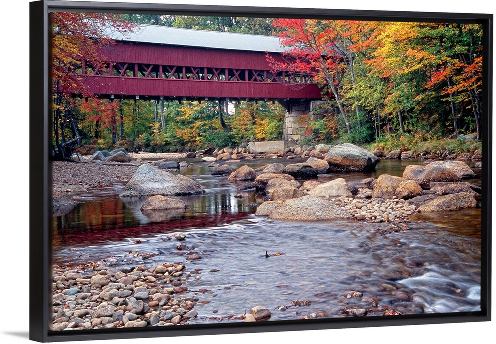 Photograph of the wooden Swift River Bridge located in Conway, New Hampshire that overlooks a river flowing through rocks ...