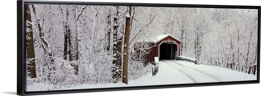 Panoramic photograph of a snow covered bridge in Pennsylvania that is surrounded by a forest.