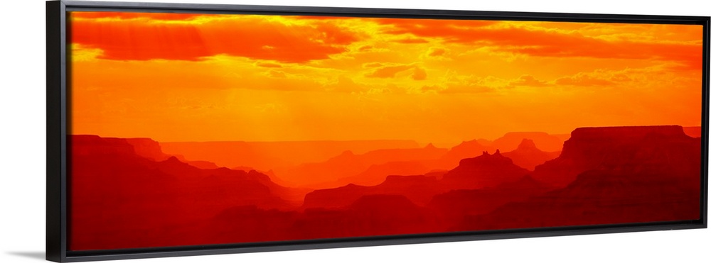 Tonal panoramic photograph of canyon silhouettes at sunrise.