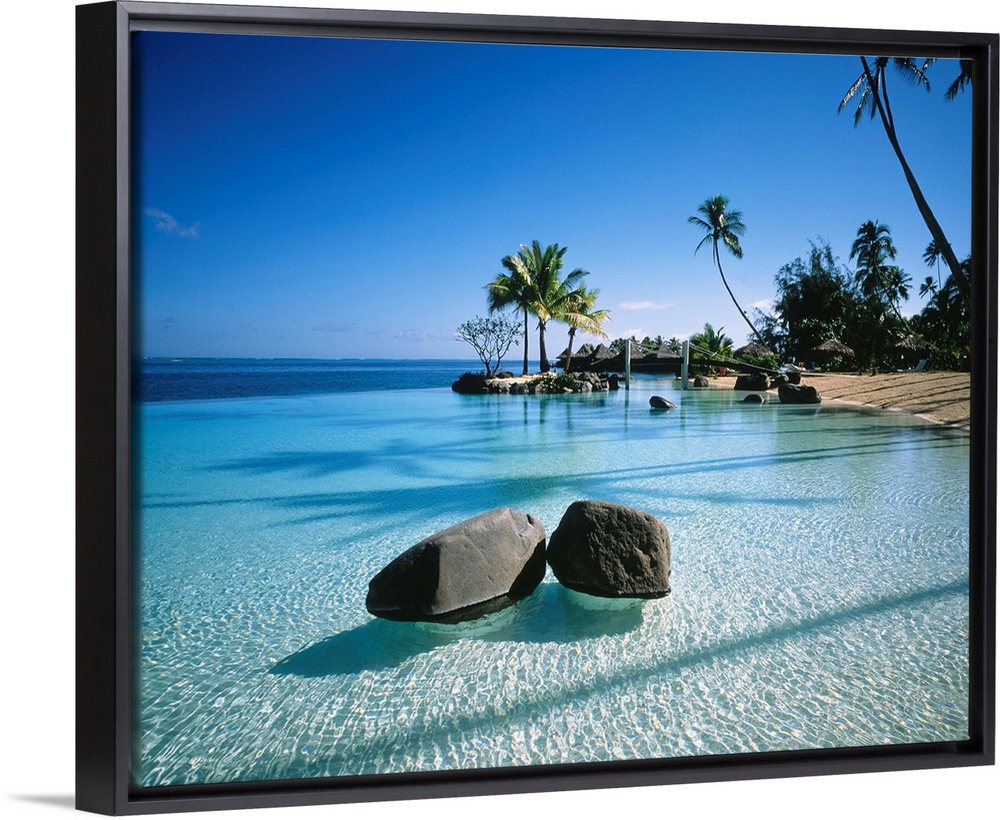 Large landscape artwork for a living room or office of clear water ripples around rocks on a tropical beach lined by palm ...