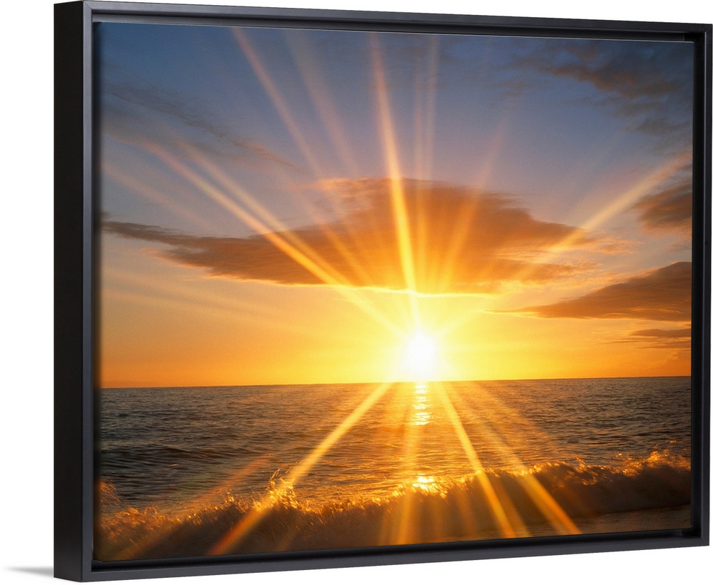 Giant photograph of a bright sunset reflecting onto an ocean as the waves crash against a sandy beach.