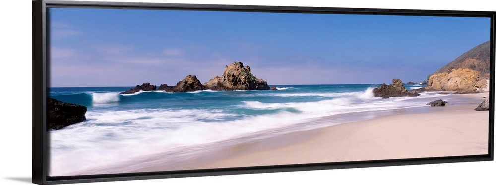 Panoramic photographs displays the Pacific Ocean crashing into the sandy shores of this beach.  Located near the shore are...