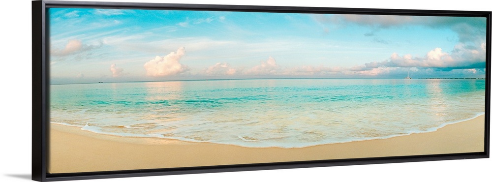 A wide angle panoramic wall hanging of a calm tropical ocean, waves on the beach, and cumulus clouds near the horizon.