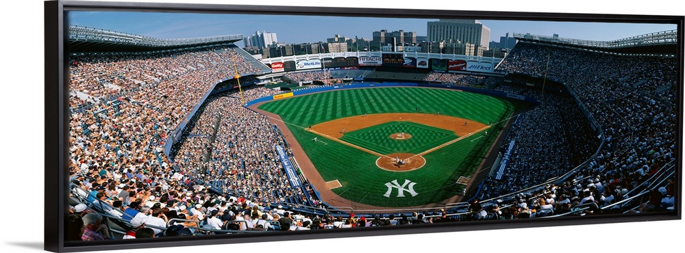 Panoramic photograph taken at Yankee Stadium in the Bronx, New York displays fans enjoying a baseball game on a sunny day....