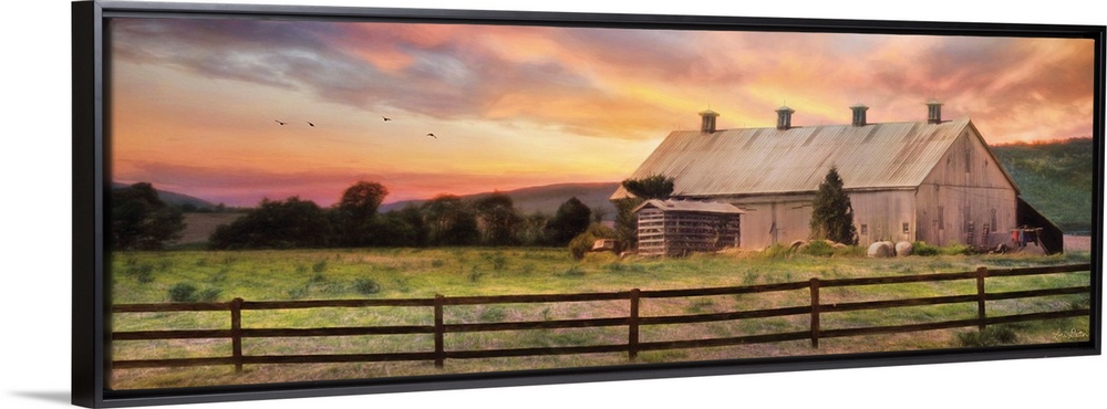 A barn in the countryside with a wooden fence in the early evening.