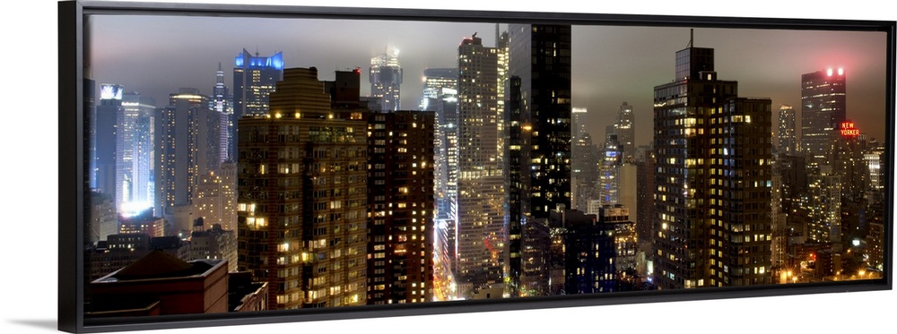 Panoramic photo of the New York city skyline with skyscrapers lit up at night.