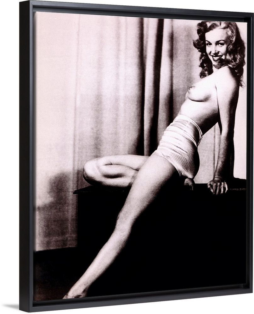Boudoir photo of Marilyn Monroe topless and leaning back on a stand in front of a curtain, smiling at the camera.