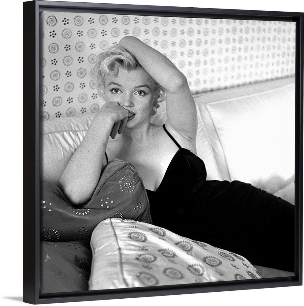 Wall art of Marilyn Monroe sitting on a sofa looking at the camera.