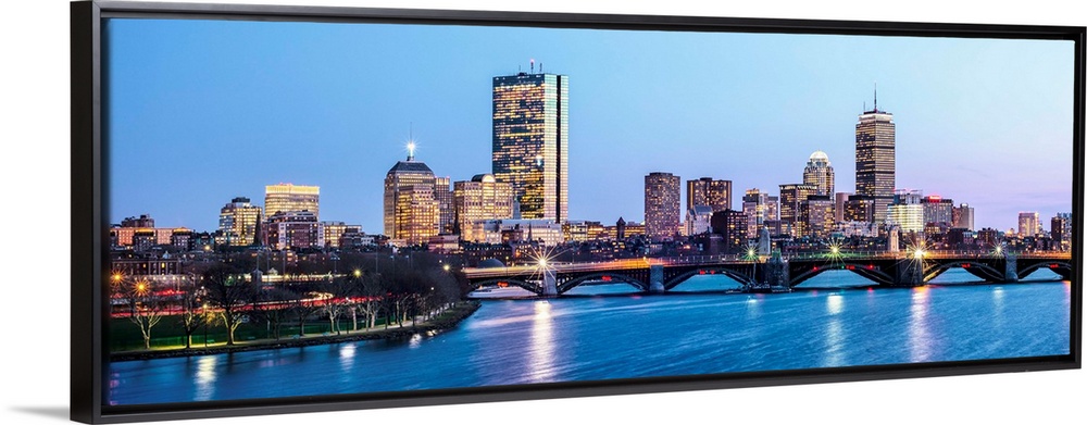 Panoramic view of the Boston City skyline illuminated at night, with the Longfellow Bridge in the foreground.