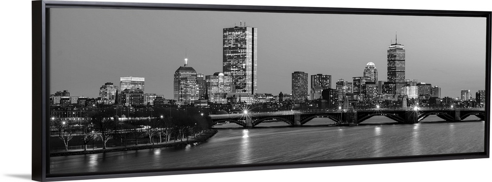 Panoramic view of the Boston City skyline illuminated at night, with the Longfellow Bridge in the foreground.