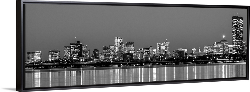 Panoramic view of the Boston City skyline at night, with lights reflected in the water.