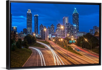 Busy freeway with light trails, with the Atlanta, Georgia skyline in the distance