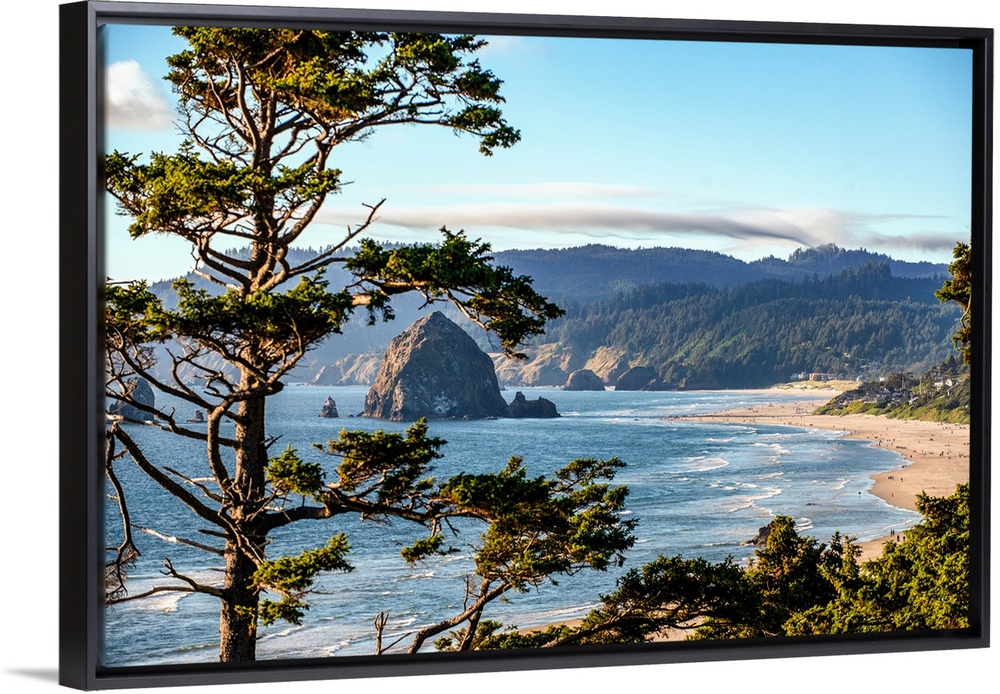 Landscape photograph of Cannon Beach through trees with Haystack Rock in the distance.