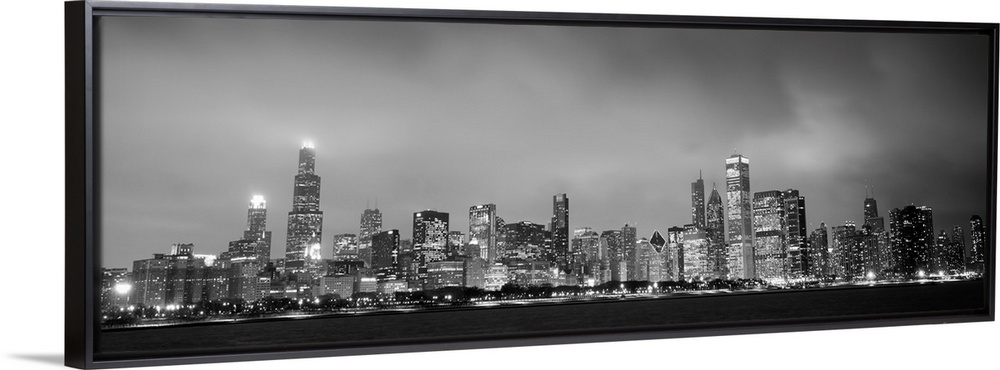 Panoramic view of the Chicago city skyline in the early evening, with city lights reflecting off the clouds above.