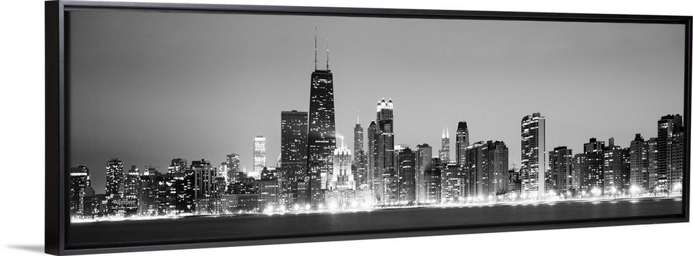 Panoramic view of the Chicago city skyline illuminated in the early evening, seen from across the water.