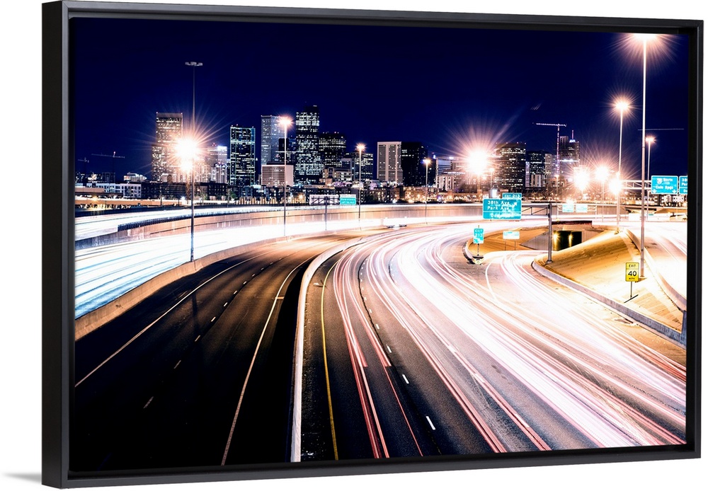 Photo of light trails against Denver's night skyline.