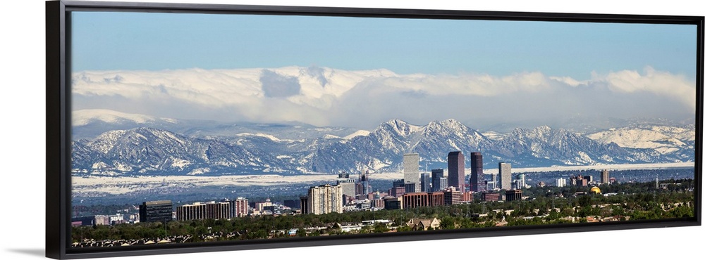 Panoramic photo of a Denver skyline against a backdrop of the Rocky Mountains.